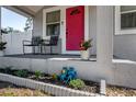 Close-up of the front porch, featuring decorative plants and a bright pink entry door at 6907 N 12Th St, Tampa, FL 33604