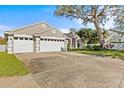 Spacious three-car garage with wide driveway and mature landscaping at 726 Hidden Lake Dr, Tarpon Springs, FL 34689