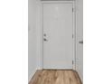 A white front door with a modern handle and peephole, complemented by wood flooring at 108 Pompano Se Dr # A, St Petersburg, FL 33705