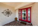 Close-up of the bright red front door with glass panels and decorative wall art at 1113 Carlton Rd, Tarpon Springs, FL 34689