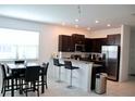 Modern kitchen with stainless steel appliances, dark cabinets, and granite countertops with bar seating at 14352 Editors Note St, Ruskin, FL 33573