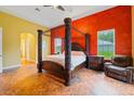 Bedroom with a red accent wall, tile floors, and a canopy bed next to a brown leather chair at 15618 Phillips Rd, Odessa, FL 33556