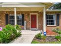 Welcoming front porch with brick accents, decorative plants, and a bright red front door at 1805 Parkwood Dr, Valrico, FL 33594