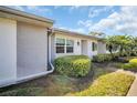 Villa with inviting front entrance with landscaped bushes in front of the multiple windows at 3401 Stonehaven E Ct # A, Palm Harbor, FL 34684