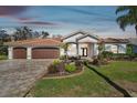 Spacious home with three-car garage, tile roof, and manicured front lawn at 3819 Brooksworth Ave, Tarpon Springs, FL 34688