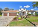 Beautifully landscaped home with a brick driveway, lush lawn, and a three-car garage at 3819 Brooksworth Ave, Tarpon Springs, FL 34688