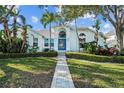 Inviting two-story home with a blue door, beautiful landscaping, and a well-maintained lawn at 436 3Rd N Ave, Tierra Verde, FL 33715