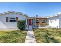 Charming single-story home featuring a red front door, a brick accent wall, and a well-manicured lawn at 5881 31St N Ave, St Petersburg, FL 33710