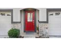 Charming red front door framed by stone accents and gray trim, flanked by two garage doors at 1208 Chatham Pine Pl, Brandon, FL 33511