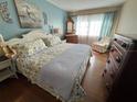 Cozy bedroom featuring a floral patterned bed, wooden dresser, and natural light from the window at 1235 S Highland Ave # 1-204, Clearwater, FL 33756