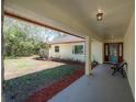 Inviting covered front porch with a bench and view of the front yard and wooded area at 16740 Monteverde Dr, Spring Hill, FL 34610