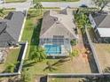 Aerial view of a backyard featuring a screened-in pool, surrounded by tropical landscaping and fencing at 22516 Magnolia Trace Blvd, Lutz, FL 33549