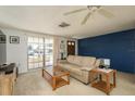 Cozy living room with neutral carpet, and a sofa bathed in natural light, accentuated by a blue accent wall at 6905 El Camino Paloma St, Port Richey, FL 34668