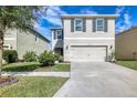Beautiful two-story home with a spacious driveway, manicured lawn, and gray exterior paint at 16849 Trite Bend St, Wimauma, FL 33598