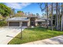 Charming single-story home with a three-car garage, manicured lawn, and beautiful landscaping at 3137 Valemoor Dr, Palm Harbor, FL 34685