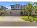 Two-story home featuring a three-car garage, brick accents, and a well-manicured lawn at 3148 Marine Grass Dr, Wimauma, FL 33598