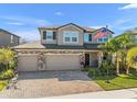 Two-story home featuring a three-car garage, brick accents, and a well-manicured lawn at 3148 Marine Grass Dr, Wimauma, FL 33598
