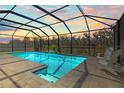 Enclosed screened pool area featuring tile floors and a view of the trees in the back at 3148 Marine Grass Dr, Wimauma, FL 33598