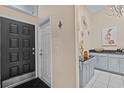 Inviting entryway with black front door, leading to a kitchen area with white cabinets and black countertop at 39650 Us Highway 19 N # 244, Tarpon Springs, FL 34689