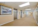 Hallway with beige walls leading to elevators features framed art and decorative lighting at 400 64Th Ave # 1108, St Pete Beach, FL 33706