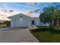 Charming single-story home at dusk features a light blue exterior, manicured lawn, and a one-car garage at 4390 6Th Isle Dr, Hernando Beach, FL 34607