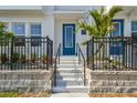 Inviting townhome entrance with vibrant blue door, black iron fencing, and manicured landscaping at 4717 W Mccoy St # 9, Tampa, FL 33616