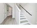Staircase with white risers and gray treads with a black handrail and light colored laminate flooring at 4717 W Mccoy St # 9, Tampa, FL 33616