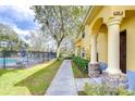 Exterior view of a yellow townhouse near a pool, featuring a sidewalk, landscaping, and a visible unit number at 6262 Timberly Ln # 99, Zephyrhills, FL 33542