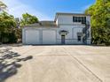 Two-story light-blue home with white garage doors, gray roof, concrete driveway, and spiral staircase at 920 E Lake Dr, Tarpon Springs, FL 34688