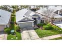 Aerial view of a well-maintained home with a gray roof, green lawn, and lush landscaping at 5351 Lookout Pass, Wesley Chapel, FL 33544