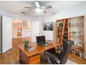 Bright home office features a wood desk, shelving, and view of the entryway and kitchen at 5351 Lookout Pass, Wesley Chapel, FL 33544