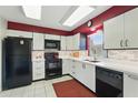 Bright kitchen with white cabinets, black appliances, and a modern backsplash for a sleek and functional cooking space at 858 Cambridge Ct # 858, Dunedin, FL 34698