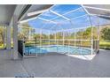 Screened-in pool area with tiled flooring, safety fence, and views of the serene backyard and pond at 10218 Garden Alcove Dr, Tampa, FL 33647