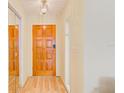 Bright entryway featuring a wood door with decorative panels, wood floors, and mirrored closet doors at 1831 Kay Dr, Largo, FL 33770