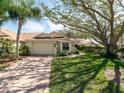 Well-maintained single-story home with an attached garage, brick driveway, and established trees at 2503 New Haven Cir, Sun City Center, FL 33573