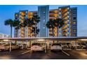 Exterior view of the condo building, Marina Tower, at dusk with lights on and covered parking with several cars at 2530 Gary Cir # 401, Dunedin, FL 34698