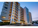 Exterior view of the condo building, Marina Tower, at dusk with lights on and landscaping at 2530 Gary Cir # 401, Dunedin, FL 34698