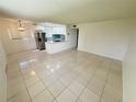 Bright living room with tile flooring and an open view into the modern kitchen with stainless steel appliances at 3300 Fox Chase N Cir # 229, Palm Harbor, FL 34683