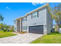 Front exterior of a gray home featuring a stone facade, driveway and manicured lawn at 3709 W Dale Ave, Tampa, FL 33609