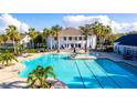 Expansive community pool with ample seating, surrounded by palm trees and a beautiful clubhouse at 5513 Creek Ridge Rd, Brooksville, FL 34601