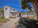 Charming home with a mix of white wood and stone facade, complemented by lush landscaping at 590 Baywood N Dr, Dunedin, FL 34698