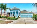 Beautiful blue home featuring a spacious three-car garage and a welcoming front porch at 613 Manns Harbor Dr, Apollo Beach, FL 33572