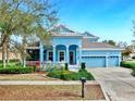 Charming two-story home with a well-manicured lawn, a welcoming front porch, and a three car garage at 613 Manns Harbor Dr, Apollo Beach, FL 33572