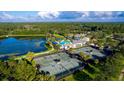 Scenic aerial view of the community amenities, featuring tennis courts, lake, pool, and clubhouse surrounded by lush landscaping at 6614 Summit View Dr, Brooksville, FL 34601