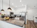 Bright kitchen features stainless steel appliances, granite countertops, white cabinetry, and wood-look flooring at 6930 Ripple Pond Loop, Zephyrhills, FL 33541