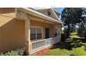 A cozy front porch with white railings, a teal door, and a view of the landscaped front yard at 8906 Iron Oak Ave, Tampa, FL 33647