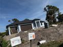 Contemporary home under construction featuring a two-car garage, modern windows and door framed with blue sky at 9 Tee View Rd, Rotonda West, FL 33947