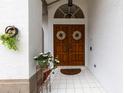 Inviting front entrance with double doors, decorative wreaths, tiled floor, and a charming floral display at 9408 Bluebird Dr, Tampa, FL 33647