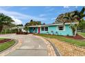 Charming curb appeal with a vibrant turquoise exterior, pink door, and meticulously landscaped walkway at 1471 Bass Blvd, Dunedin, FL 34698