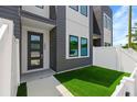 Inviting entrance with modern door, artificial turf, and white fence creating a welcoming outdoor space at 2808 N Florida Ave, Tampa, FL 33602